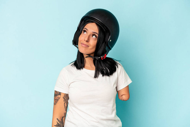 Young caucasian woman with one arm wearing a motorcycle helmet isolated o blue background dreaming of achieving goals and purposes - Foto, Imagen