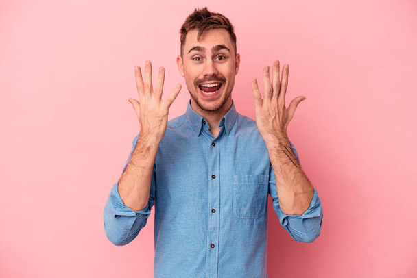 Young caucasian man isolated on pink background showing number ten with hands. - Foto, immagini