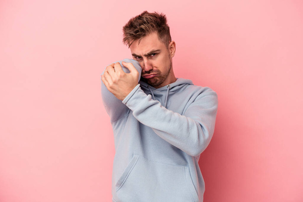 Young caucasian man isolated on pink background having a neck pain due to stress, massaging and touching it with hand. - Photo, Image