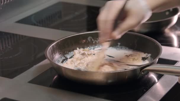 Cocina de restaurante - chef mezcla setas y salsa de crema en una sartén - Imágenes, Vídeo