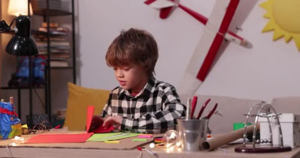 jeune garçon pliant un avion en papier et des navires, garçon causasien jouant avec des avions en papier, futur ingénieur concepteur, passe-temps - Séquence, vidéo