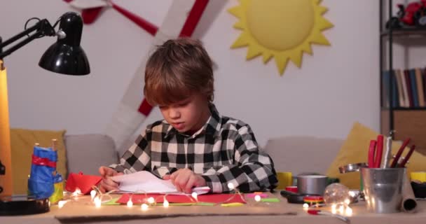 kleiner Junge faltet Papierflugzeug und Schiffe, Kaukasus-Junge spielt mit Papierflugzeugen, zukünftiger Ingenieur-Designer, Hobby - Filmmaterial, Video