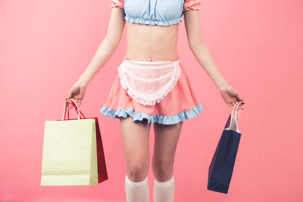 Jugador de disfraces sosteniendo las bolsas de regalo sobre fondo rosa - parte media del cuerpo - Foto, imagen