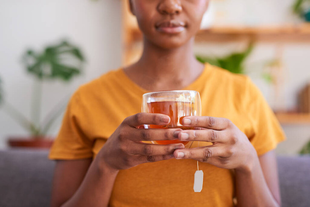 Een jonge vrouw maakt een kopje rooibos of rode bush thee voor gezondheid en welzijn - Foto, afbeelding