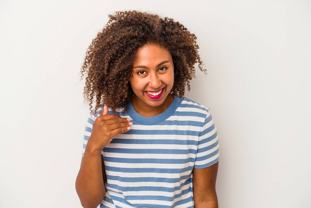 Jeune femme afro-américaine aux cheveux bouclés isolé sur fond blanc riant de quelque chose, couvrant la bouche avec les mains. - Photo, image
