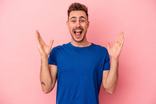 Young caucasian man isolated on pink background receiving a pleasant surprise, excited and raising hands. - Foto, immagini