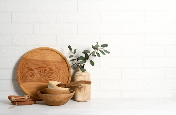 Arrangement of wooden tableware on white brick wall background - Fotografie, Obrázek