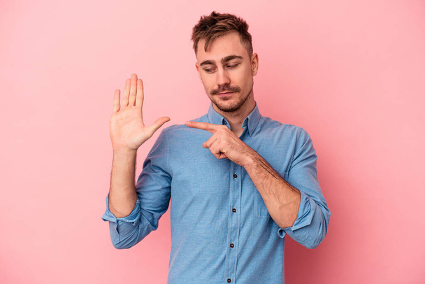 Young caucasian man isolated on pink background smiling cheerful showing number five with fingers. - Photo, image