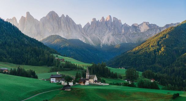 Panorama of Saint Magdalena church in Dolomites. Green grass on the hills and ancient church behind which mountain. South Tyrol, Val di Funes,  Dolomites Alps in Italy - Photo, Image