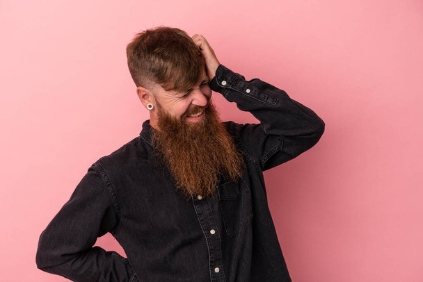 Young caucasian ginger man with long beard isolated on pink background having a neck pain due to stress, massaging and touching it with hand. - Photo, Image