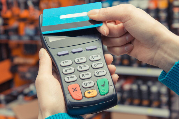 Hand of woman using payment terminal with contactless credit card. Cashless paying for shopping in shop. Finance concept - Φωτογραφία, εικόνα