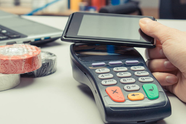 Hand of woman using payment terminal and smartphone. Contactless payment. Cashless paying for shopping in shop. Finance concept - Foto, afbeelding