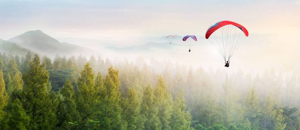 空をパラグライダー。パラグライダーの上空を飛ぶ風景太陽セット極端なスポーツの概念は、冒険の挑戦を取る.  - 写真・画像