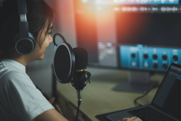 Asijská žena nosí sluchátka a zpívat píseň zvuk s mikrofonem a používat počítačový nahrávací hudební program. zvukařka nahrávat hudbu. - Fotografie, Obrázek