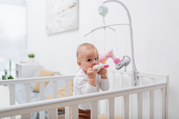 Малыш кусает игрушку в кроватке дома  - Фото, изображение