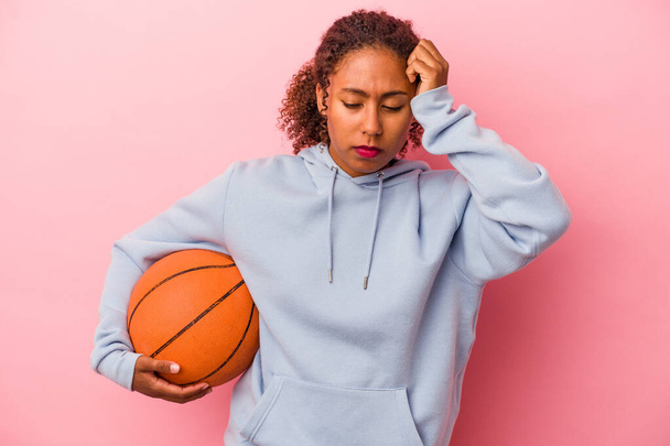 Young african american man playing basketball isolated on pink background being shocked, she has remembered important meeting. - Foto, Imagem