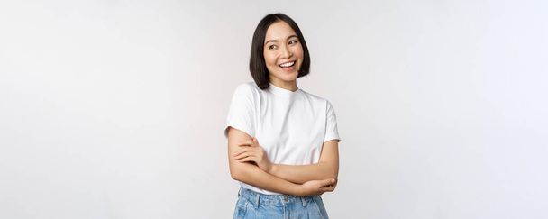 Portrait de femme asiatique heureuse souriante, posant confiante, bras croisés sur la poitrine, debout sur fond de studio - Photo, image