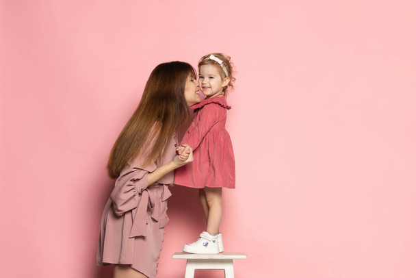 Delighted young woman and toddler, caring mother and daughter isolated on pink studio background. Mothers Day celebration. Concept of family, childhood, motherhood - Foto, Imagen
