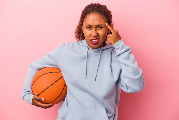 Young african american man playing basketball isolated on pink background showing a disappointment gesture with forefinger. - Fotografie, Obrázek