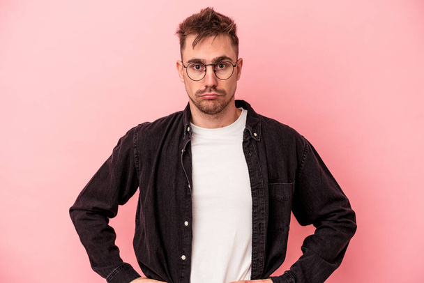Young caucasian man isolated on pink background confused, feels doubtful and unsure. - Foto, afbeelding