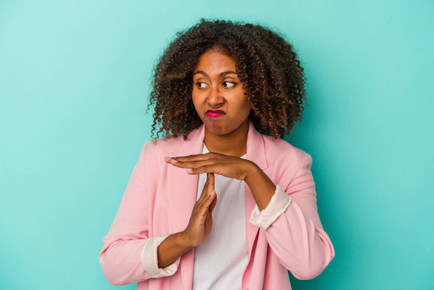 Mladý africký americký žena s kudrnaté vlasy izolované na modrém pozadí ukazující timeout gesto. - Fotografie, Obrázek
