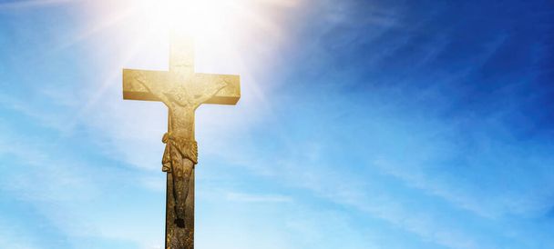 Paskalya dini arkaplan tebrik kartı - İsa 'nın Golgota' da çarmıha gerilmesi ve dirilmesi (Golgotha), İsa Mesih ile haç, mavi bulutlu gökyüzü ve haçın üzerinde parlak güneş ışığı - Fotoğraf, Görsel