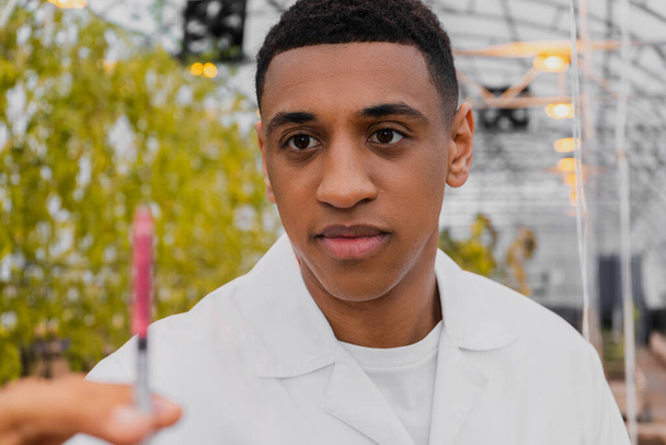African american botanist holding blurred syringe in greenhouse  - Photo, Image