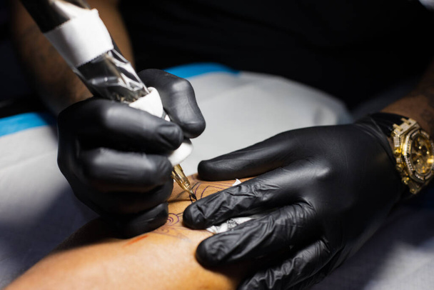 Tetoválóművész kezei fekete kesztyűben a tetoválószalonban..  - Fotó, kép