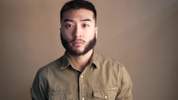 retrato asiático barbudo hombre sonriendo en marrón fondo - Imágenes, Vídeo