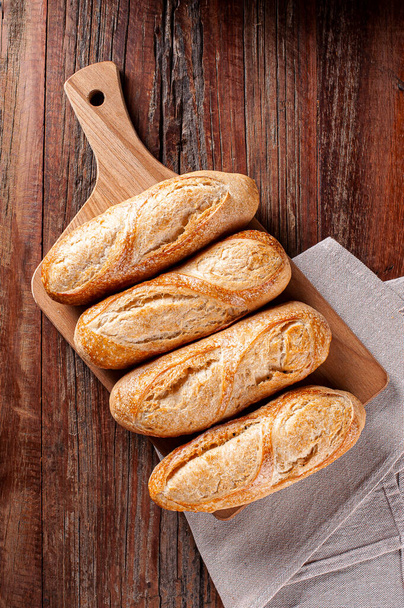 Franse stokbrood op houten plank. Bovenaanzicht. Kopieerruimte - Foto, afbeelding