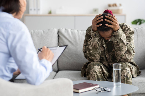 Portrét deprimované africké americké vojačky, která má terapeutické sezení s psychologem - Fotografie, Obrázek