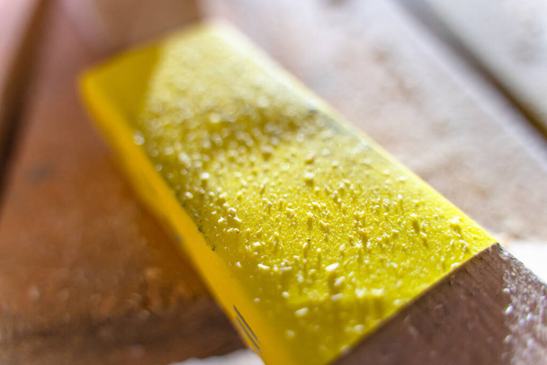 Yellow sandpaper of fine fraction close-up.Sanding paper on a wooden block - Photo, Image