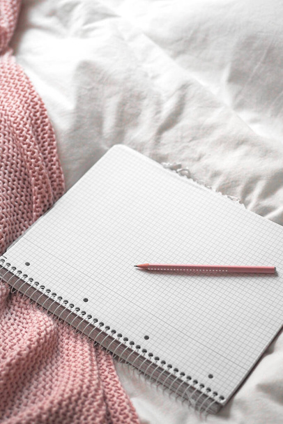 primer plano de un cuaderno blanco con un bolígrafo en una cama - Foto, imagen