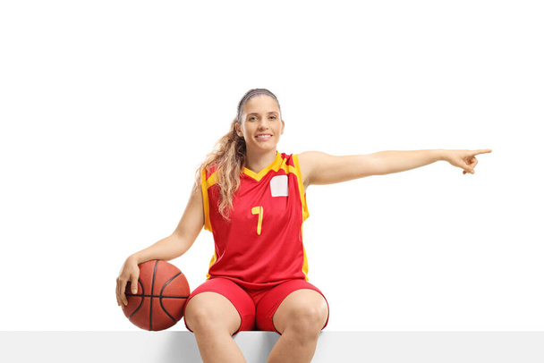 Female basketball player on a blank board pointing to the side isolated on white background - Zdjęcie, obraz