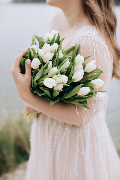Big beautiful bouquet of white tulips in the hands of the bride - 写真・画像