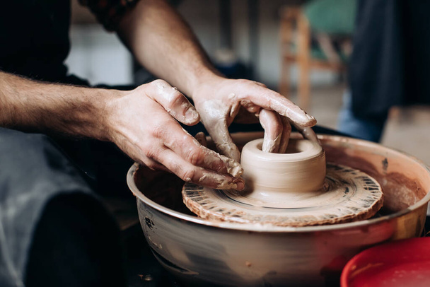 A potter on a potter's wheel makes a jug - Foto, Bild