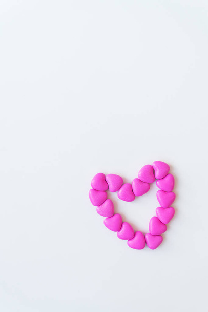 Día de San Valentín patrón de fondo plano laico vista superior de corazón en forma de caramelos rosados dispersos sobre fondo blanco - Foto, Imagen