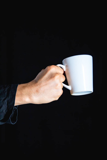 hand holding a cup of coffee on a black background - Foto, Imagem
