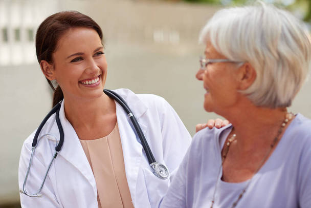 Kind and caring professional. Shot of a smiling doctor conversing with a senior patient. - Photo, Image