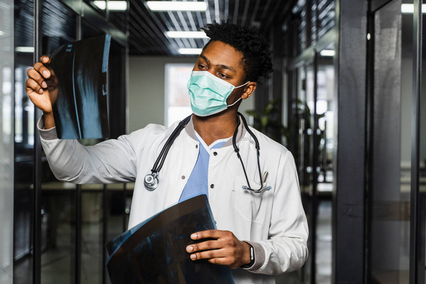 Африканський лікар оглядає рентгенівські промені в медичній клініці. Чорний учень у медичній масці вивчає і дивиться Ст-сканування - Фото, зображення