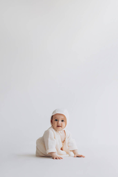 Cute studio portrait of a little newborn girl posing for a photo on a light background. A baby who has already learned to crawl and sit - Fotoğraf, Görsel
