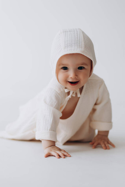 Cute studio portrait of a little newborn girl posing for a photo on a light background. A baby who has already learned to crawl and sit - Photo, image