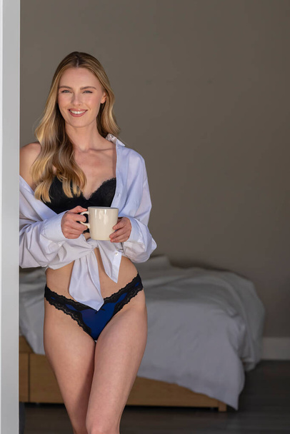 Een prachtig blond model poseert in lingerie in een thuisomgeving - Foto, afbeelding