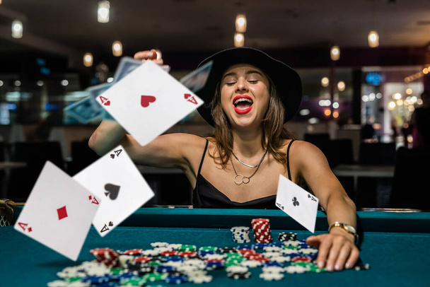 Sexy žena hraje poker v elegantních černých šatech v klubovně. koncept hazardních her - Fotografie, Obrázek