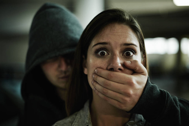 Nein, das kann nicht passieren. Eine verängstigte junge Frau, die von einem Mann mit der Hand über dem Mund gefangen gehalten wird. - Foto, Bild