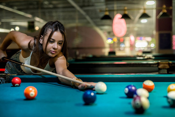 jugador femenino jugando al billar y apuntando a la pelota de billar, estilo de vida - Foto, Imagen