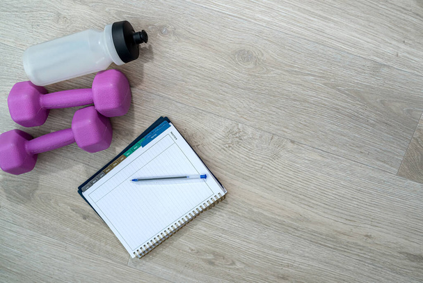 beautiful sports equipment in the form of water balls dumbbell notebook and handles lie on the floor. Sports equipment concept on background - Photo, Image