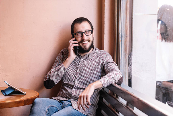 Fiatal fehér férfi mosolyog boldog beszél az okostelefonon - Fotó, kép