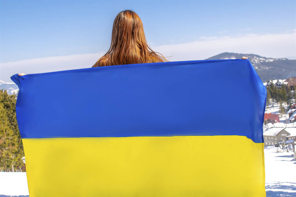 Vrouw vasthouden, fladderen, zwaaien Oekraïense nationale blauwe gele vlag.Oorlog, conflict, militaire invasie kevers Rusland als terroristische agressieve land en Oekraïne.Oekraïense onafhankelijkheid, constitutionele dag. - Foto, afbeelding