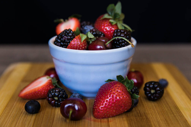 fresh berries in a bowl on a wooden table - Foto, Imagen